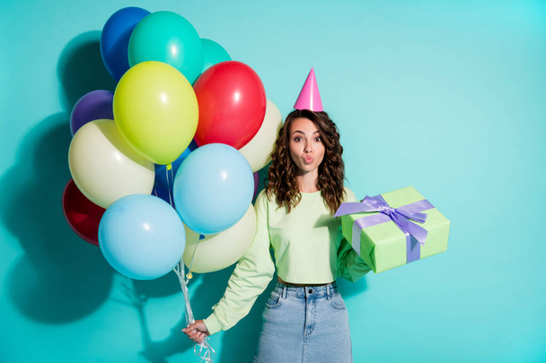 Photo of lady hold present many balloons send air kiss wear cone cap green sweater jeans short skirt isolated blue color background - Foto, imagen