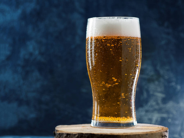 Sklenice ledově studeného ležáckého piva s kapkami vody na tmavém pozadí zblízka - Fotografie, Obrázek