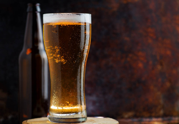 Ein Glas kaltes, helles Bier auf dunklem, rostigem Metallhintergrund - Foto, Bild