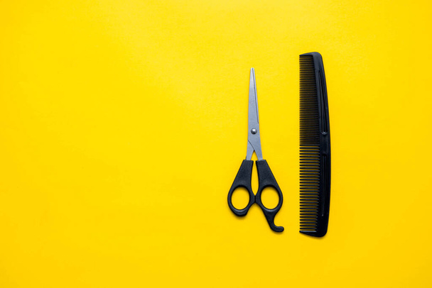 Scissors and comb for hairdresser on a yellow background. Top view. Copy, empty space for text. - 写真・画像