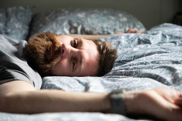 Όμορφος άντρας χαλαρώνει στο κρεβάτι ονειροπολώντας - Φωτογραφία, εικόνα