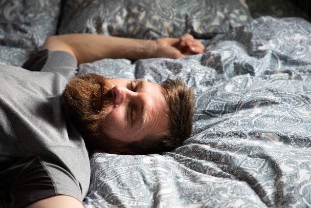 schöner Mann entspannt sich im Bett tagträumend - Foto, Bild