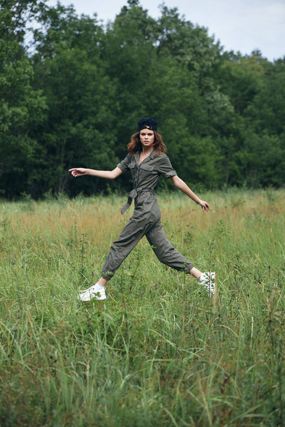 Žena na louce, skákající přes trávu, zelená kombinéza, čerstvý vzduch  - Fotografie, Obrázek