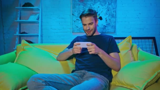 Fröhlicher Mann spielt Videospiel auf Smartphone  - Filmmaterial, Video