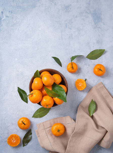 sweet and juicy tangerines in a wooden bowl and with linen napkin on a blue background. Top view and copy space - Foto, Imagen