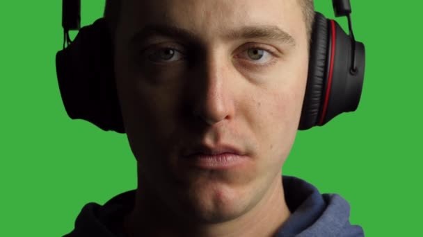 Young Man Wearing Headphones Looking at Camera, Green SCreen Background - Кадры, видео