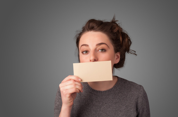 niedliches Mädchen hält weiße Karte vor ihren Lippen mit Kopierschutz - Foto, Bild
