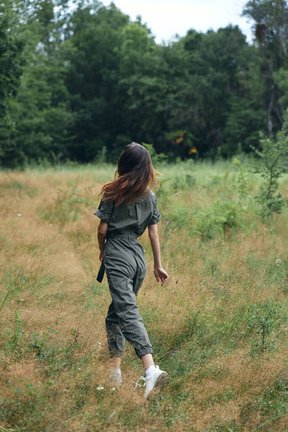 Woman walks on nature in a field of green trees - Фото, зображення