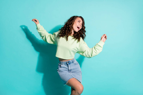 Cropped photo of pretty dreamy girl dancing on weekend singing wearing casual outfit laughing isolated on vivid teal color background - Photo, image