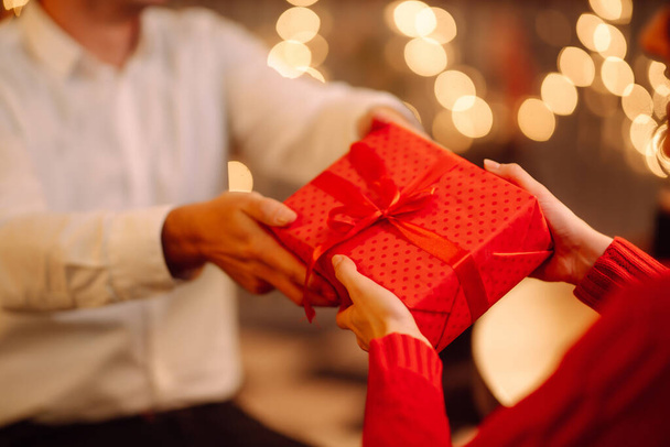 Exchange of gifts. Man gives to his woman surprise a gift box with red ribbon.Young loving couple celebrating Valentines Day. Romantic day. Winter holidays. - Fotó, kép
