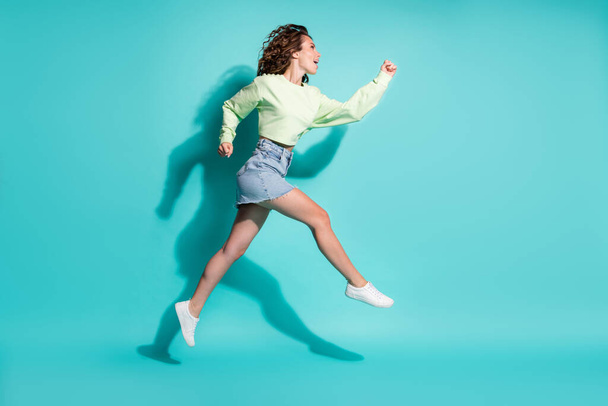 Full length body size side profile photo of beautiful girl jumping high running fast isolated on bright teal color background - Fotó, kép