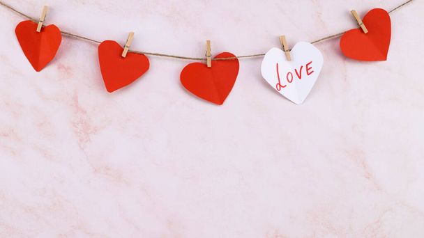  ghirlanda rossa a forma di cuore su sfondo rosa parete. Ghirlanda di San Valentino. - Foto, immagini