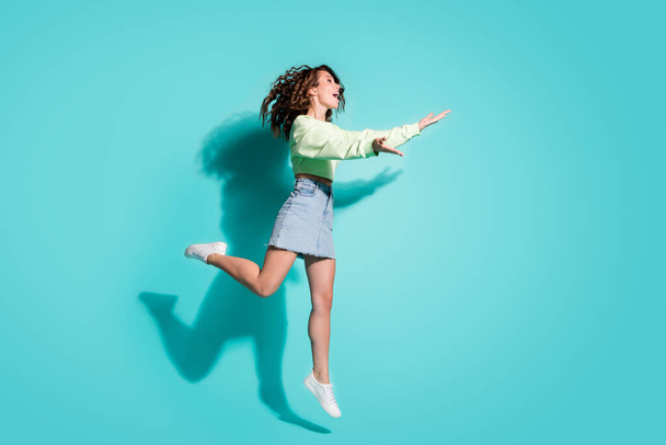 Full length body size side profile photo of girl going hug embrace catch jumping isolated on vibrant teal color background with copyspace - 写真・画像