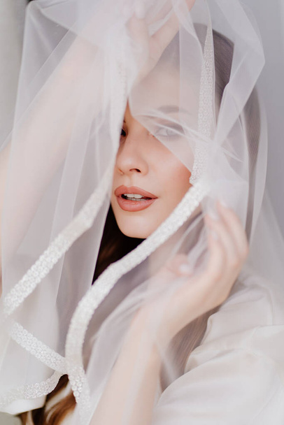 portrait of a beautiful young woman in a white robe under a wedding veil.  - Fotografie, Obrázek