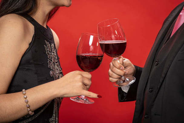 Couple in love toasting with wine glasses on red background. Valentine's Day. - Zdjęcie, obraz