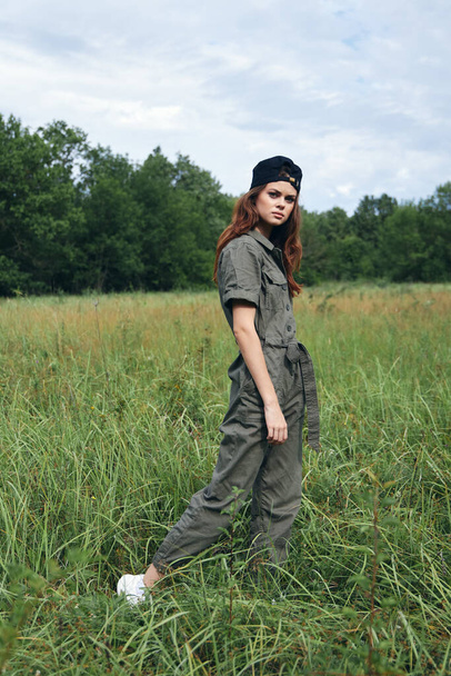 woman outdoors Tall grass in fresh air in green overalls  - 写真・画像
