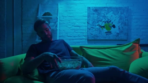 Mann mit Popcorn schaut zu Hause fern  - Filmmaterial, Video