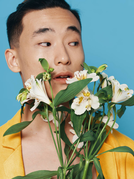 romantyczny azjatycki facet z bukietem białych kwiatów i w żółtym płaszczu modelu - Zdjęcie, obraz