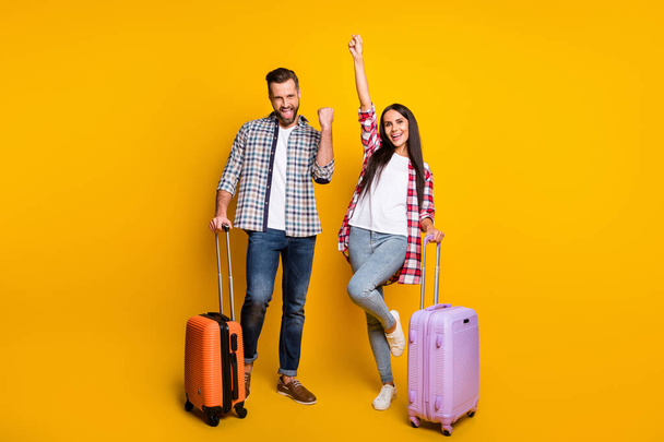 Photo portrait full body view of cheerful excited couple with suitcases isolated on vivid yellow colored background - Foto, afbeelding