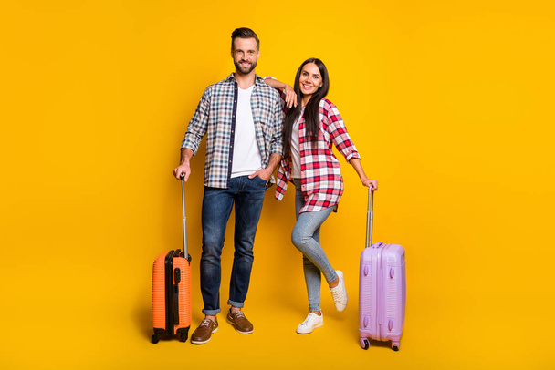 Photo portrait full body view of man and woman getting ready for trip with suitcases isolated on vivid yellow colored background - Fotografie, Obrázek