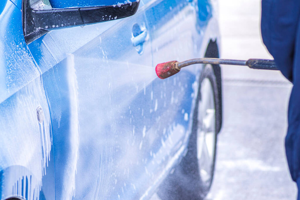 A man washes a car on his own. Car wash self-service. Cheap car wash.Man washing his car in a self-service car wash station - Φωτογραφία, εικόνα