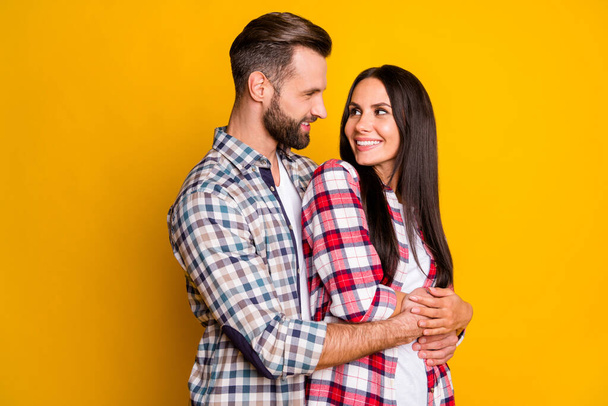 Photo portrait of man hugging woman from behind looking at each other isolated on vivid yellow colored background - Fotó, kép