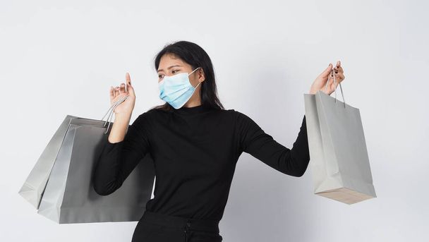 Covid 19 and shopping concept. Asian woman wearing face mask hold shopping bag. Girl and paper bag represent shopping during coronavirus crisis or covid19 outbreak. shopper and virus mask. white B - Valokuva, kuva