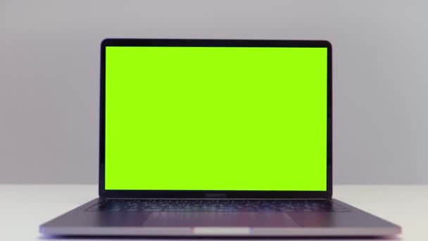 Крупный план современного ноутбука с зеленым цветным экраном, стоящим на столе на белом фоне стены. Начали. Концепция дистанционной работы и технологии. - Кадры, видео