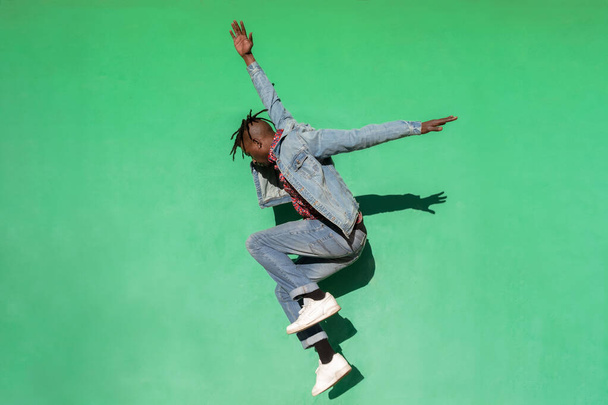 Młody Afrykanin skacze w górę odizolowany na zielonym tle. - Zdjęcie, obraz