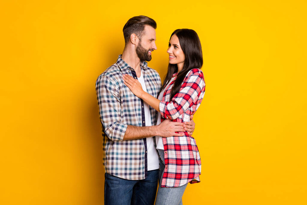 Profile side view portrait of attractive cheerful amorous couple embracing isolated over bright yellow color background - Foto, Bild