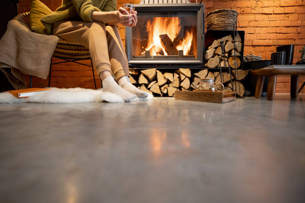Woman relaxing by a fireplace at home - Фото, зображення