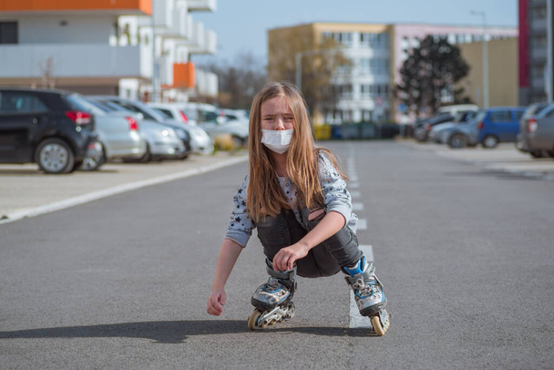 Защитная маска от аллергии на лице. Девушка на роликовых коньках в защитной маске на лице катается по улице. - Фото, изображение