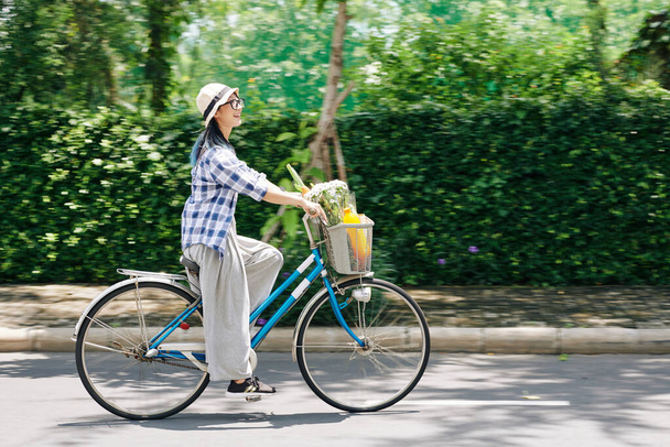 Feliz joven china disfrutando de montar en bicicleta en el parque, el movimiento borroso - Foto, Imagen