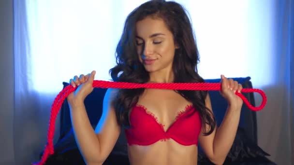 hartstochtelijke vrouw in rood lingerie houden touw in slaapkamer - Video