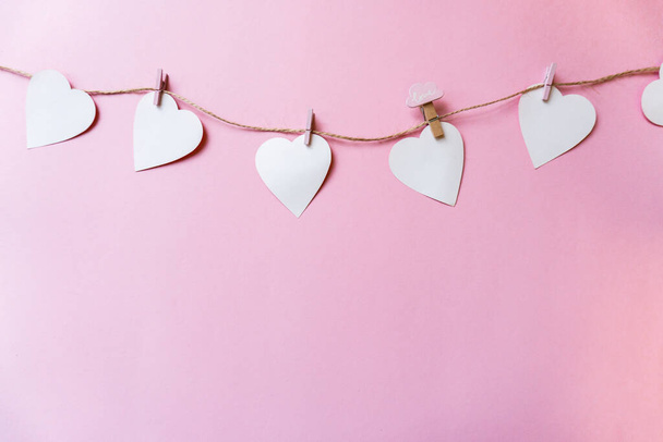 Белые бумажные сердечки висят на бельевой веревке с прищепками на р - Фото, изображение
