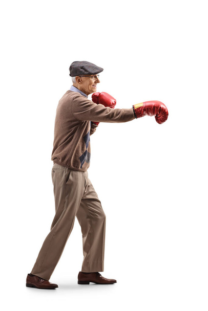 Full length profile shot of an elderly manexercising with boxing gloves isolated on white background - Foto, immagini