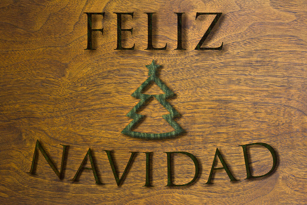 Flaga Feliz Navidad z małą choinką w ciepłym zielonym i brązowym tle drewna. - Zdjęcie, obraz