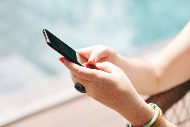 Yüzme havuzunda dinlenen, mesajlaşan ve mobil uygulama kullanan kadınların elleri - Fotoğraf, Görsel