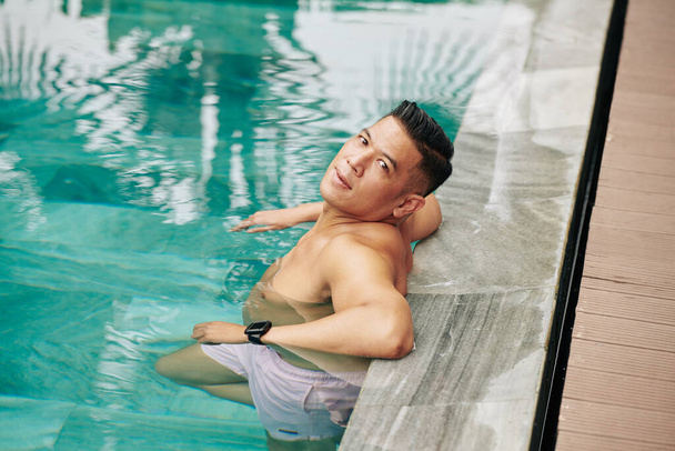暖かい日にプールでリラックスしたハンサムな筋肉アジアの男 - 写真・画像