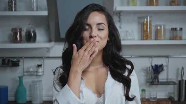 sexy, uśmiechnięta kobieta patrząc w aparat i dmuchanie pocałunki powietrza w kuchni - Materiał filmowy, wideo