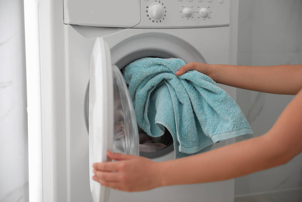 Woman putting dirty laundry into washing machine indoors, closeup - Fotó, kép