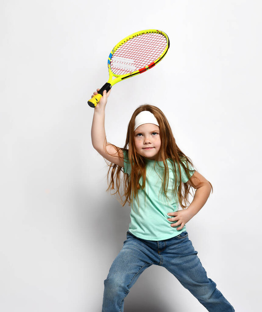Little red-haired girl child playing big tennis studio shot - Foto, Bild
