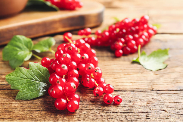 Delicious red currants and leaves on wooden table, closeup - Fotó, kép