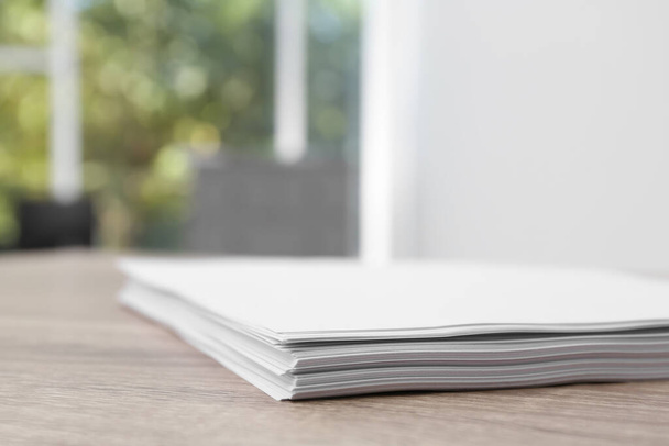 Stack of blank paper sheets on wooden table in office, closeup - Φωτογραφία, εικόνα