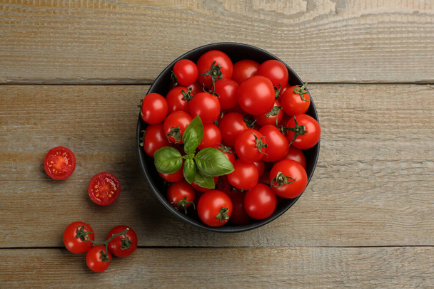 Fresh cherry tomatoes and basil leaves on wooden table, flat lay - Фото, зображення