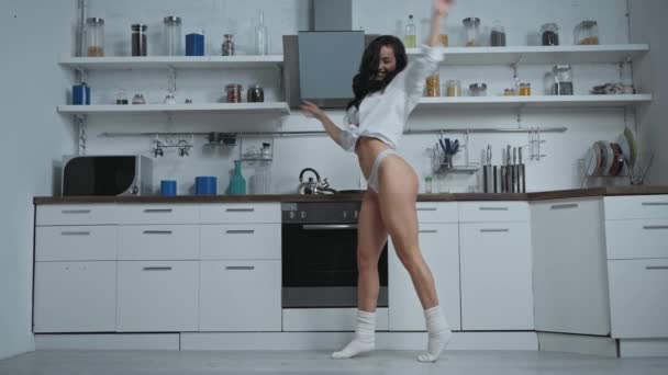 σέξι γυναίκα με πουκάμισο και κιλότα χορεύει στη μοντέρνα κουζίνα - Πλάνα, βίντεο