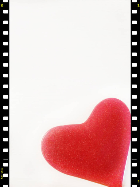 Film efektli bir çerçevede Sevgililer Günü tebrik kartı, beyaz arka planda kırmızı bir kalp, mesaj atmak için boş yer var.. - Fotoğraf, Görsel