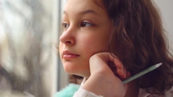 Portret marzącej nastolatki, patrzącej przez okno prosto w kamerę - Materiał filmowy, wideo