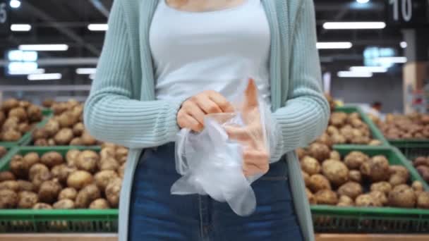 スーパーで使い捨て手袋を着用する女性のクロップドビュー  - 映像、動画