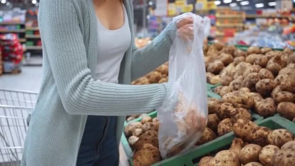 μελαχρινή γυναίκα βάζει πατάτες σε πλαστική σακούλα - Πλάνα, βίντεο